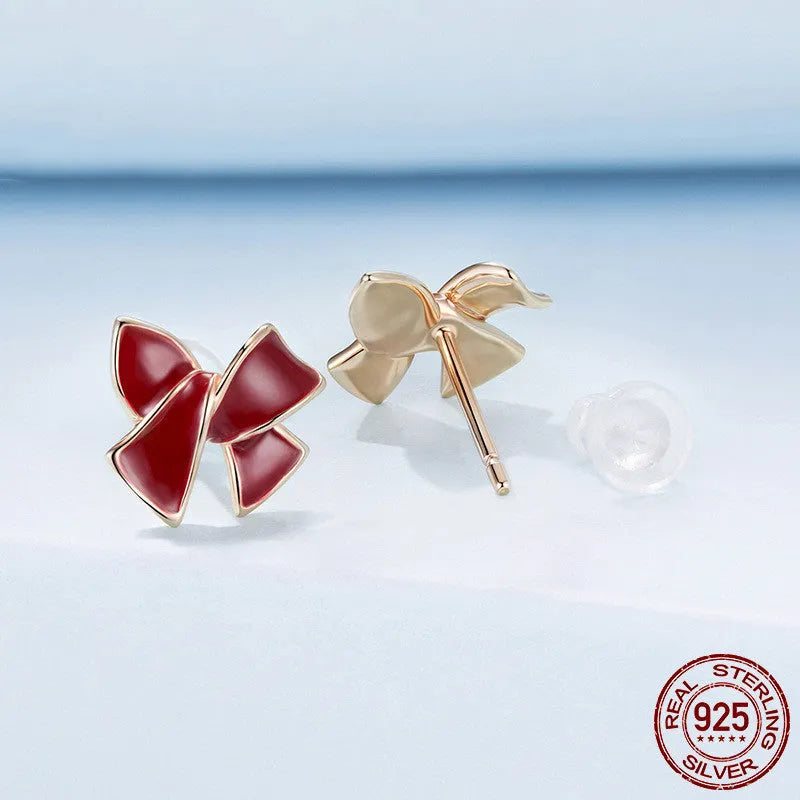 Pair of silver 925 sterling silver bow stud earrings with wine red finish on white background