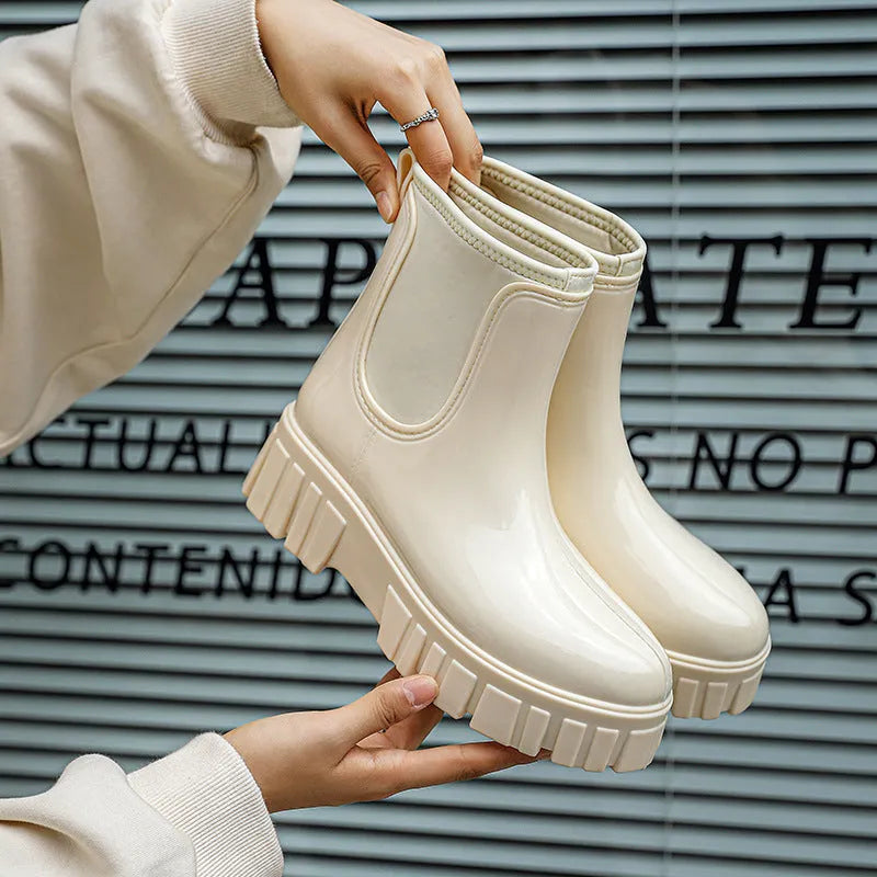 Creamy-white low tube PVC rain boot with non-slip sole on a wet surface.