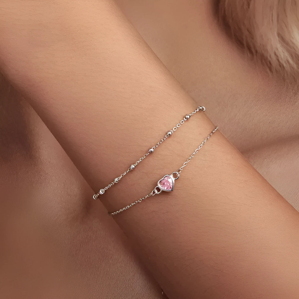 Women's sweet style sterling silver heart bracelet with adjustable chain on white background.
