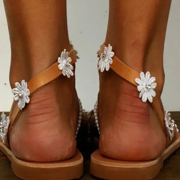 Brown Roman sandals with floral pattern, herringbone toe, and flat rubber sole