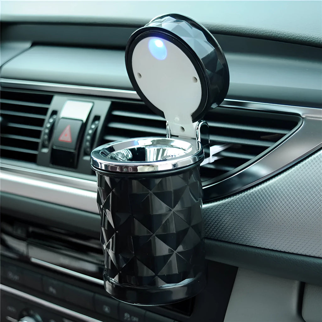 Black car ashtray made of ABS plastic hanging from a car air outlet vent.