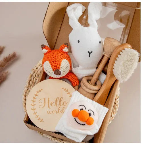 Baby teething toy gift set with bamboo blend gauze blanket, wooden beech bell, teether, brush, and milestone marker.