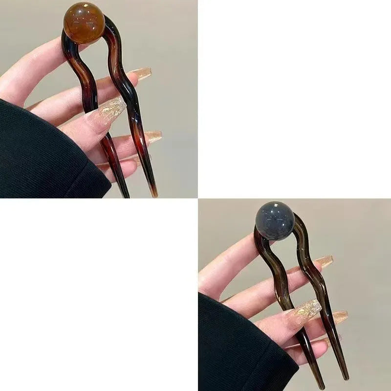 Acrylic U-shaped hair barrette with a small spherical decoration in a beige and caramel two-tone colour combination.