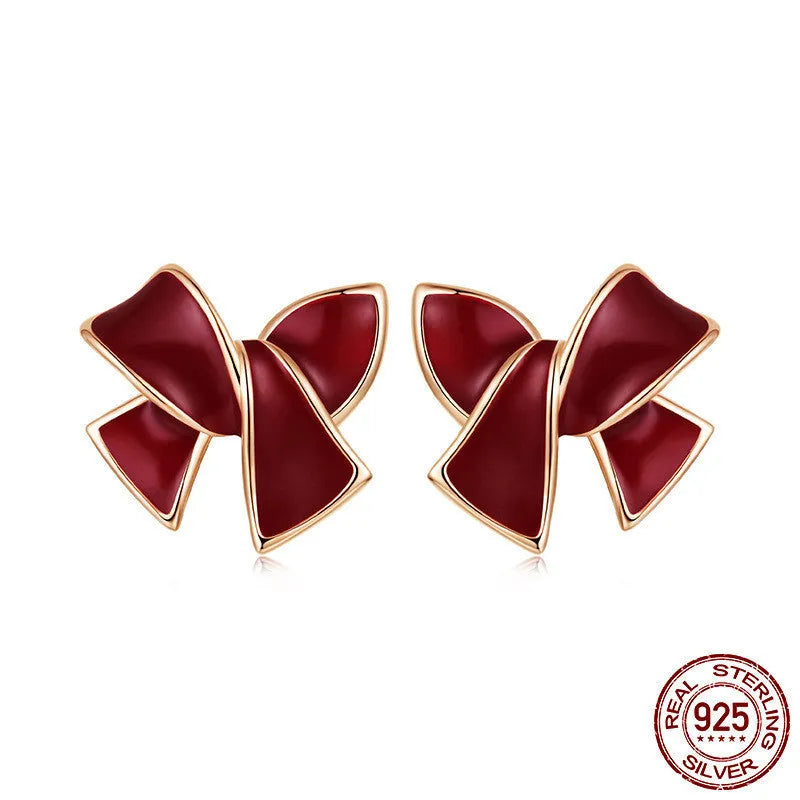 Pair of silver 925 sterling silver bow stud earrings with wine red finish on white background