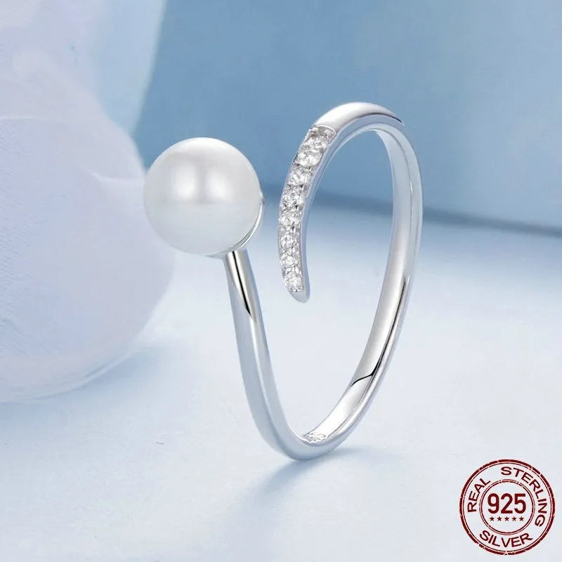 Adjustable sterling silver ring with a white shell pearl centre on an open loop band.