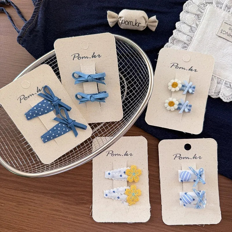 Children's denim handmade flower polka dot bow barrettes with triangle and duckbill clips on a light background