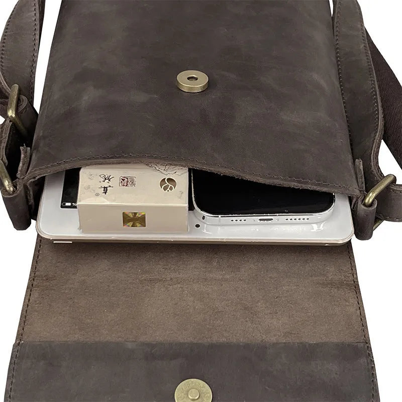 Men's brown Crazy Horse leather crossbody backpack on a plain background, showing retro design and iPad pocket