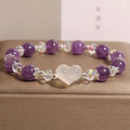 Natural amethyst bracelet with white agate love heart charm on a light background