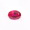 A loose, artificial pigeon blood red ruby gemstone showing a brilliant round cut on a neutral background.