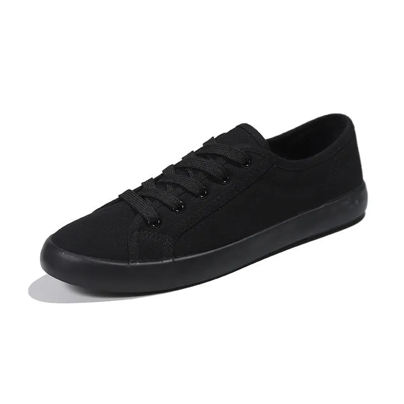 All black low top canvas lace-up shoes with a flat rubber sole for women.