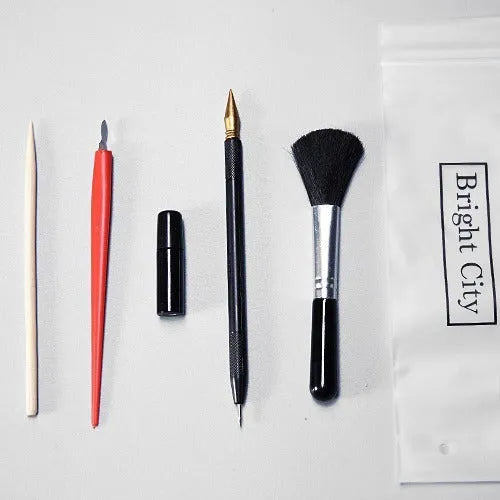 Scratch painting tools set with white card, 14.5cm long tool, brushes, and photo frames on a table.