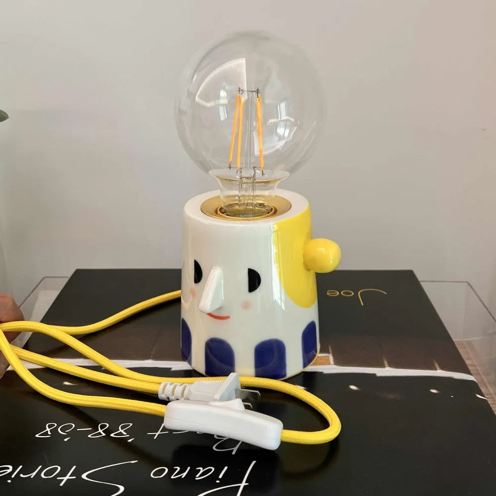 Handmade ceramic lamp with ball headlight design on wooden surface