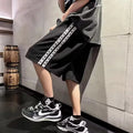 Man wearing loose black track pants with a sporty style, showing the baggy fit and micro elastic fabric.