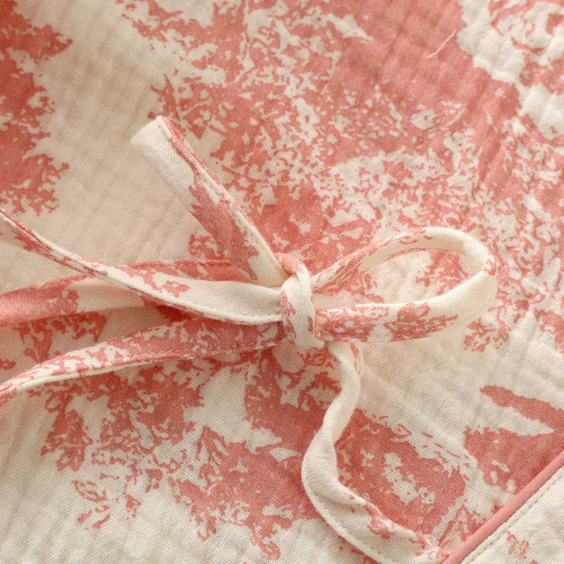 Women's pink cotton gauze lounge suit set with lace-up long sleeve top and matching trousers on a hanger.