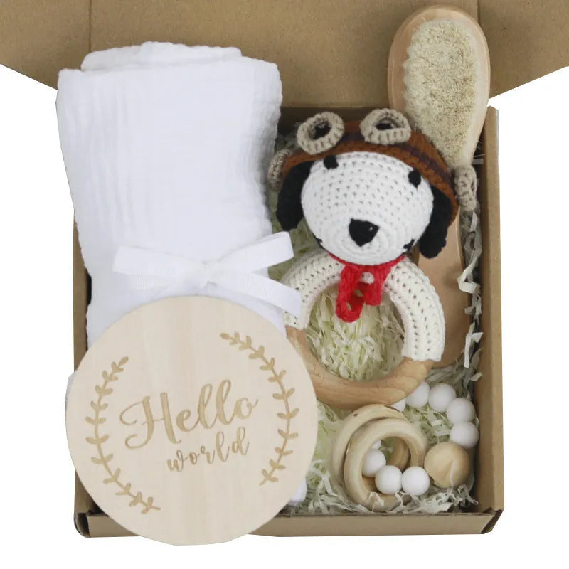Baby teething toy gift set with bamboo blend gauze blanket, wooden beech bell, teether, brush, and milestone marker.