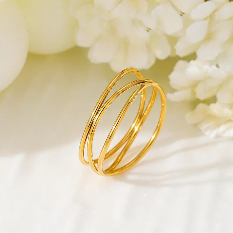Gold titanium steel women's ring with a three-layer geometric line and coiled design on a white background.