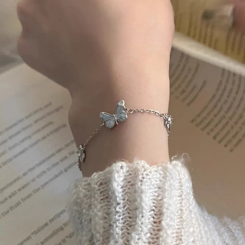 Set of 925 silver luminous butterfly bracelet necklace and earrings with floral petals on white background