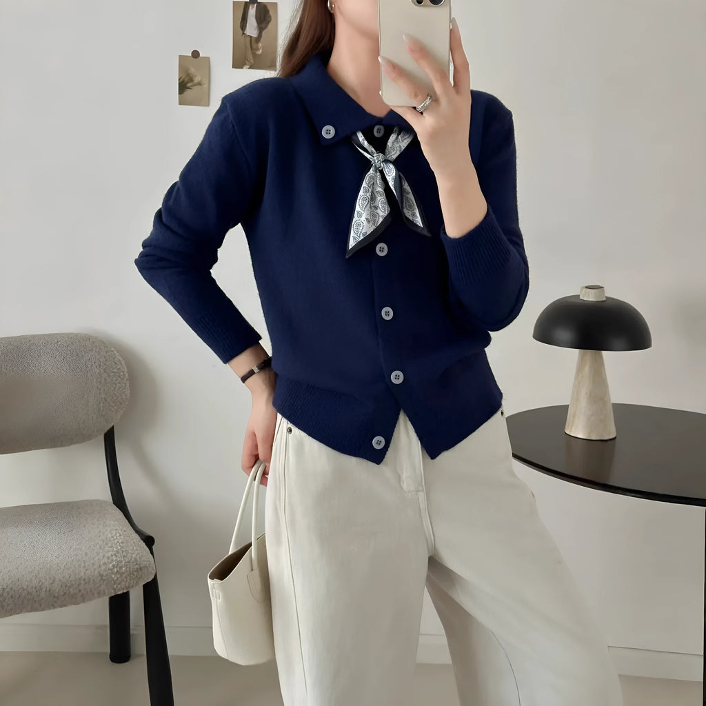 Milky white acrylic cardigan sweater with lapel collar and scarf trim detail, long sleeves.
