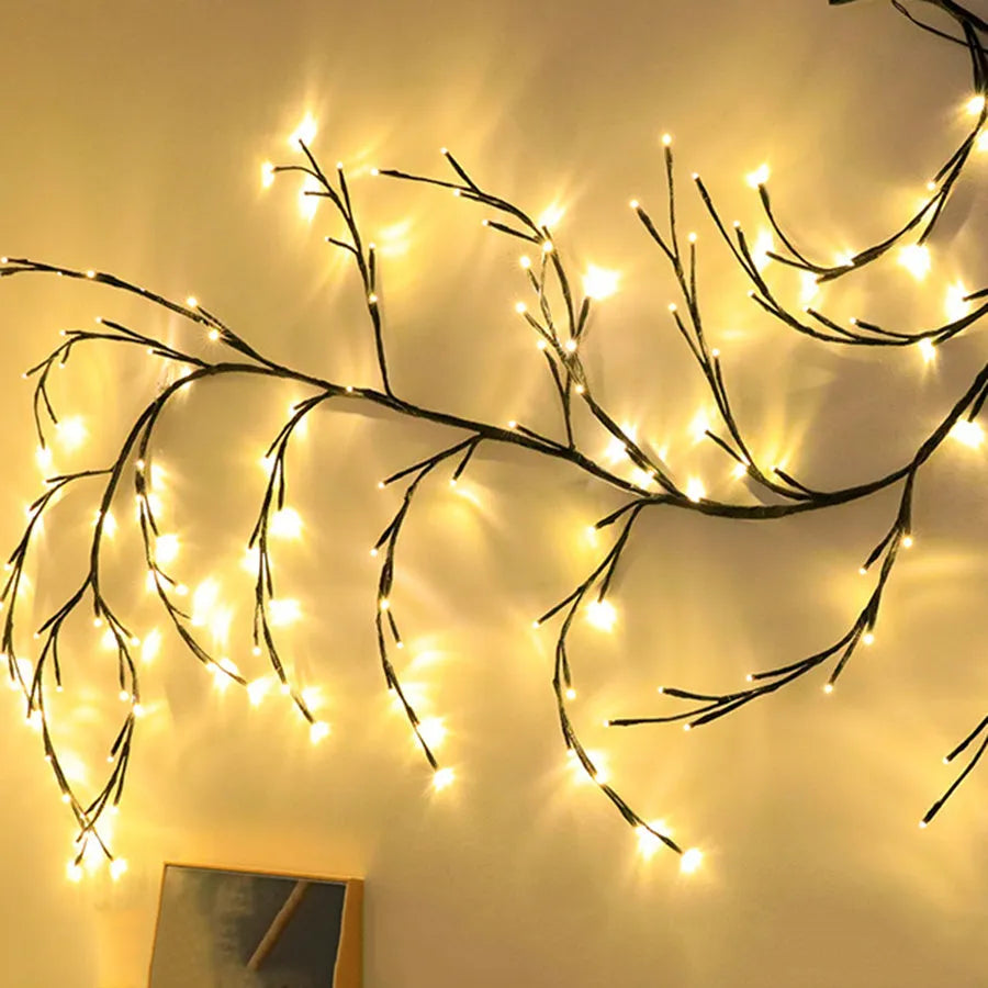 Flexible willow vine Christmas garland with warm white LED lights bent into a decorative shape on a wall.