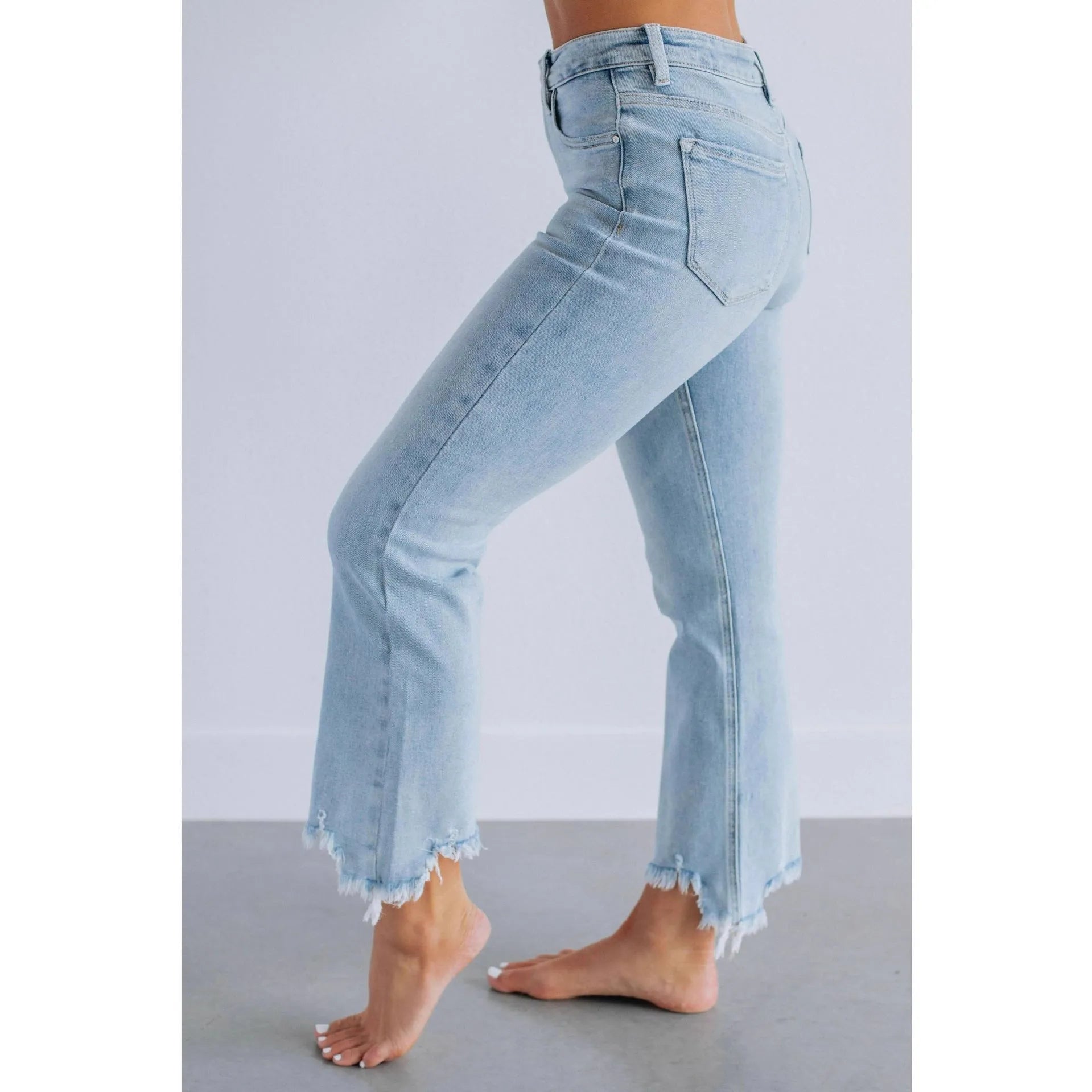 Women's dark blue denim jeans with hand-worn distressing detail on a hanger.