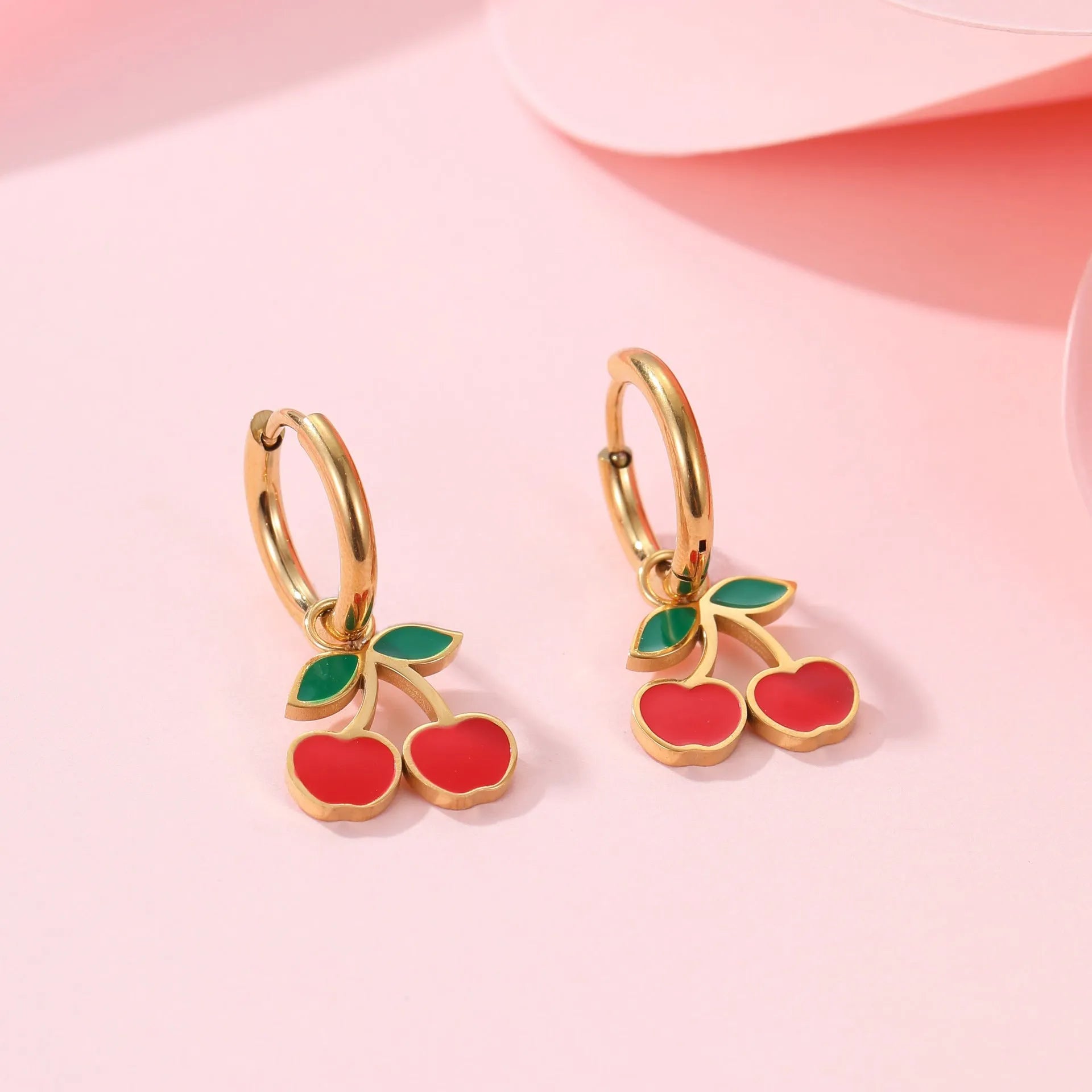 Cherry design jewellery set with gold plated necklace, bracelet, earrings, and ring on a flat surface.