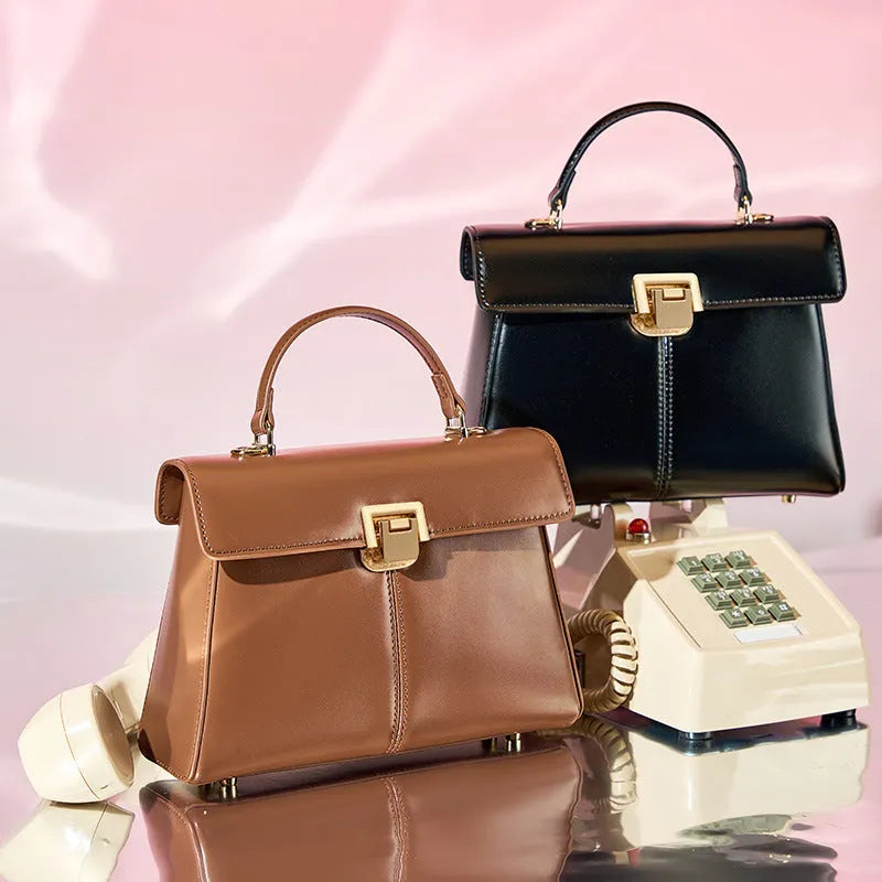 Women's black leather shoulder bag with clasp closure and adjustable strap showing interior organisation