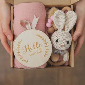 Baby teething toy gift set with bamboo blend gauze blanket, wooden beech bell, teether, brush, and milestone marker.