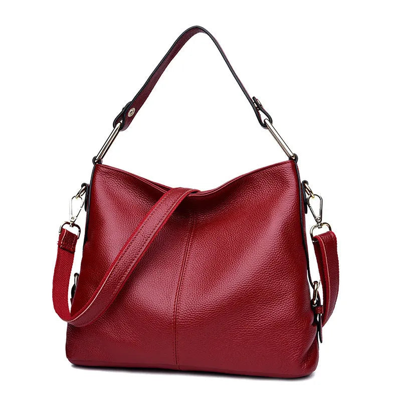 A vertical square-shaped genuine leather crossbody bag in black, showing external sewing lines and a crossbody strap.