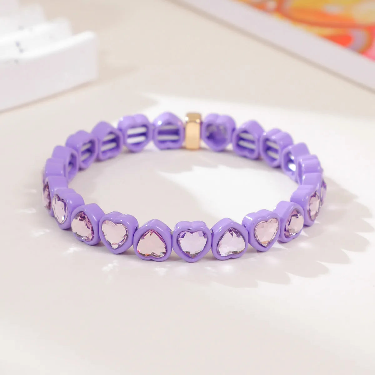 Colourful enamel finish alloy heart charm on a black stretch bracelet band.