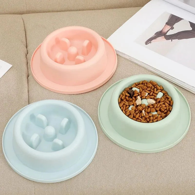 Pink pet slow feeder bowl with raised maze pattern and non-slip base on a floor