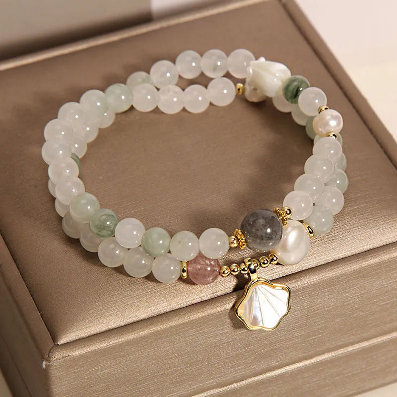 Women's crystal bracelet with gold ginkgo leaf pendant and rhinestones on a white background.