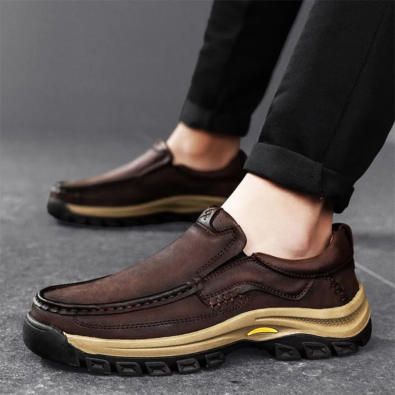 Men's black thick-soled mountaineering leather shoes with round toe and visible stitching on a natural background.