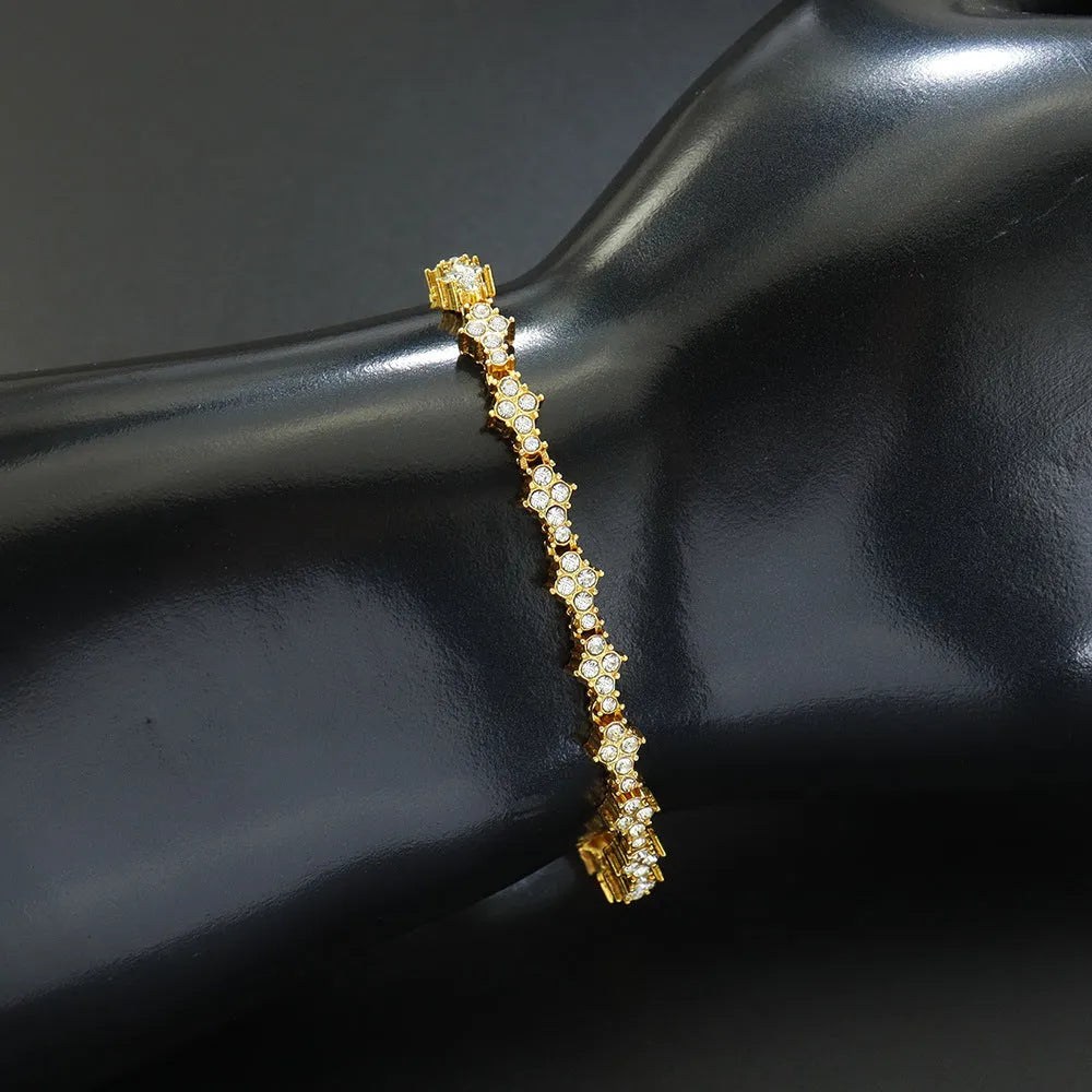 Flower-shaped cross tennis chain bracelet in gold alloy on white background showing diamond and geometric detailing