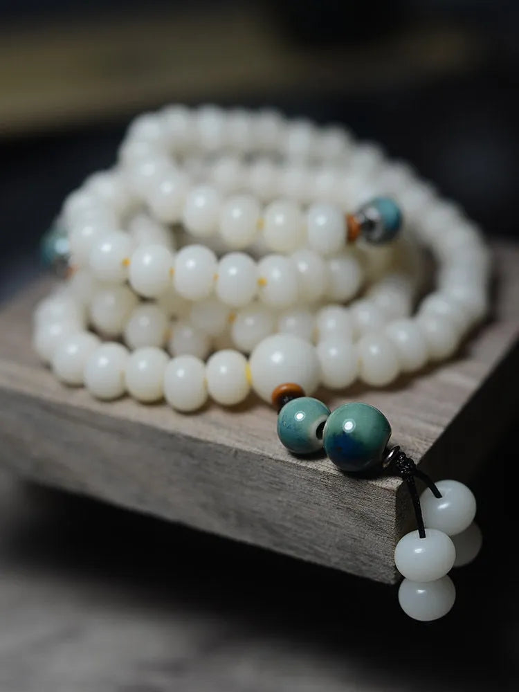 White jade bodhi seed bracelet with 108 flat round beads in two sizes on wrist