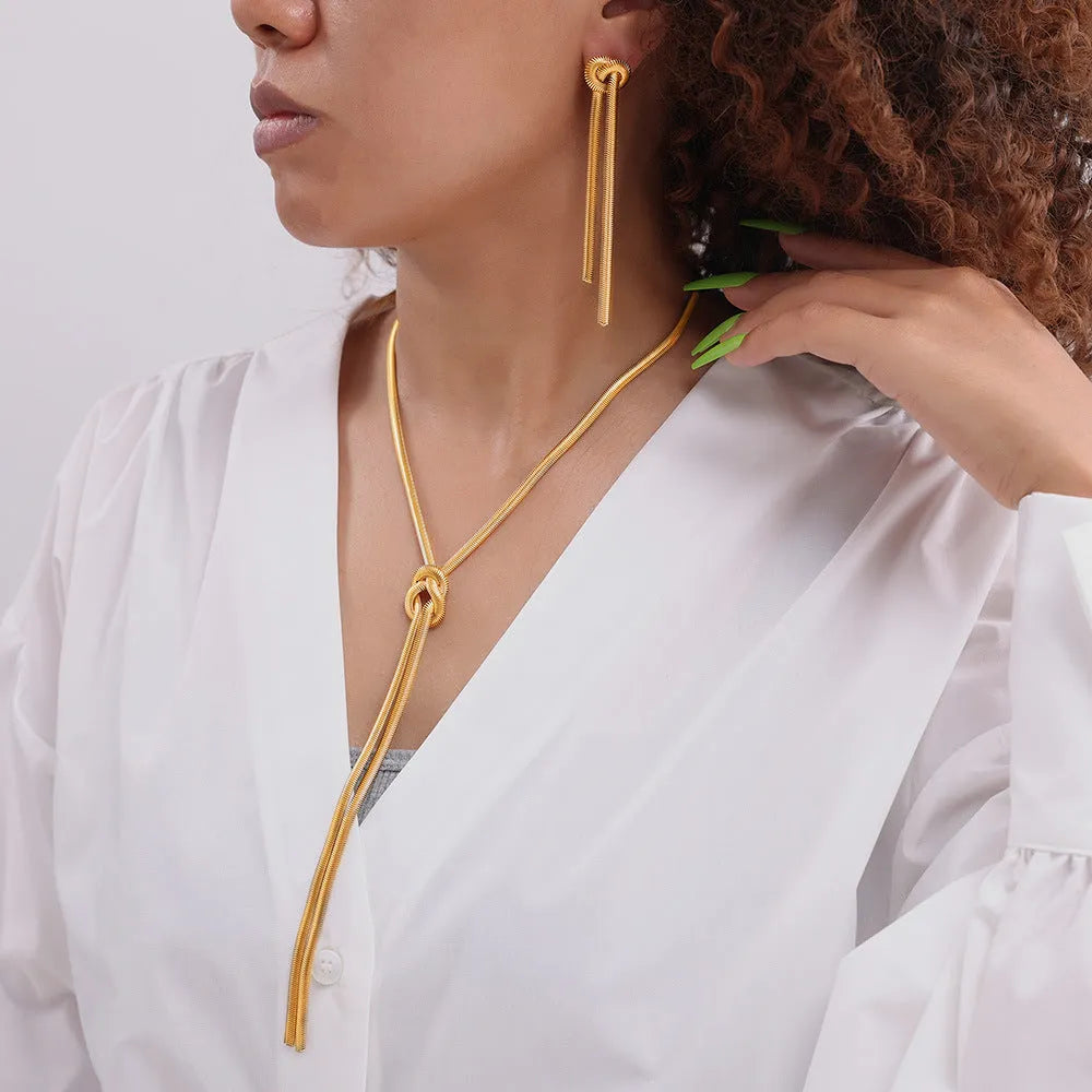 Gold knotted tassel pendant on long snake chain necklace with matching titanium steel earrings