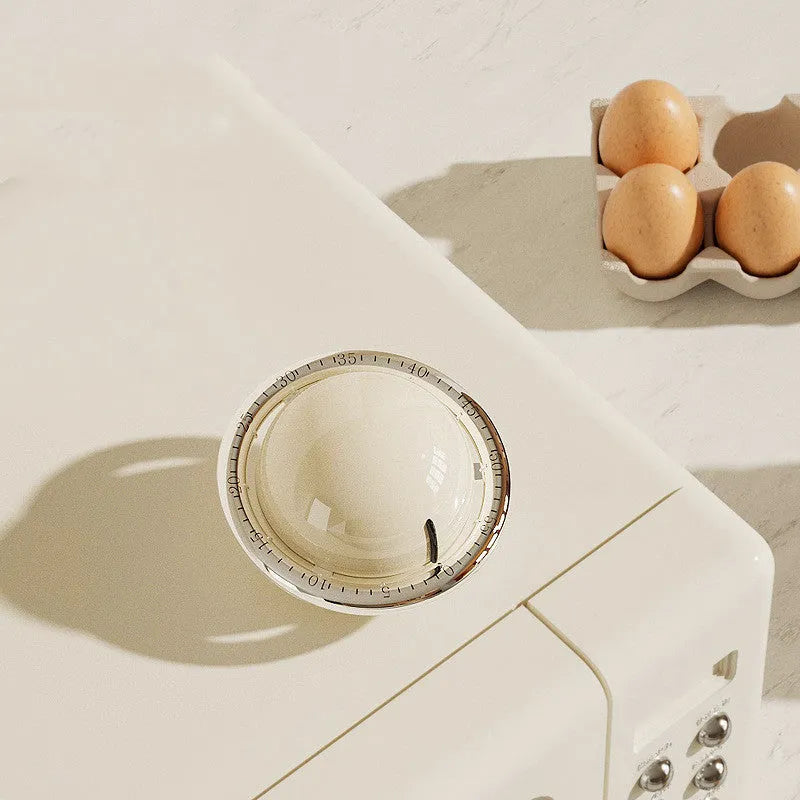 Beige mechanical kitchen timer with manual twist dial and magnetic back on metal surface