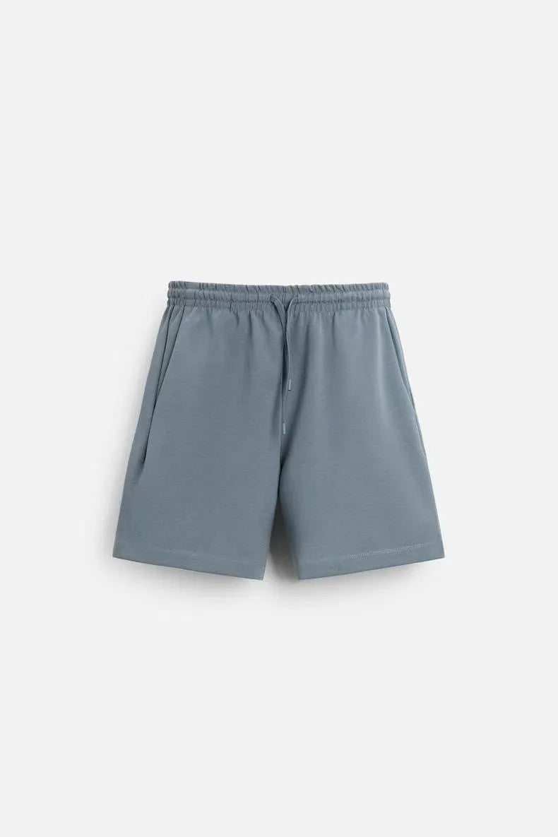 Man wearing a loose blue short sleeve top and matching blue shorts from a casual loungewear set.