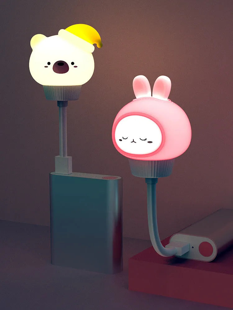 Cartoon animal USB portable LED night light with remote control on a bedside table.