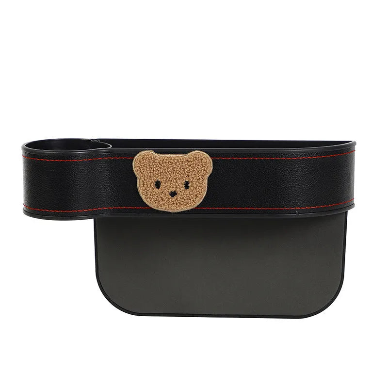 Leather car seat gap storage box with cartoon bear design, shown fitted next to a car seat.