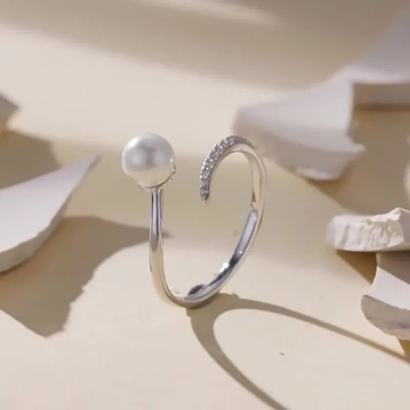 Adjustable sterling silver ring with a white shell pearl centre on an open loop band.