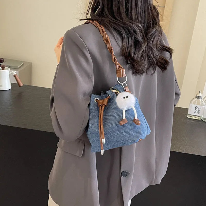 Blue one-shoulder cross body bucket bag with synthetic leather lining and hanging drop ornament