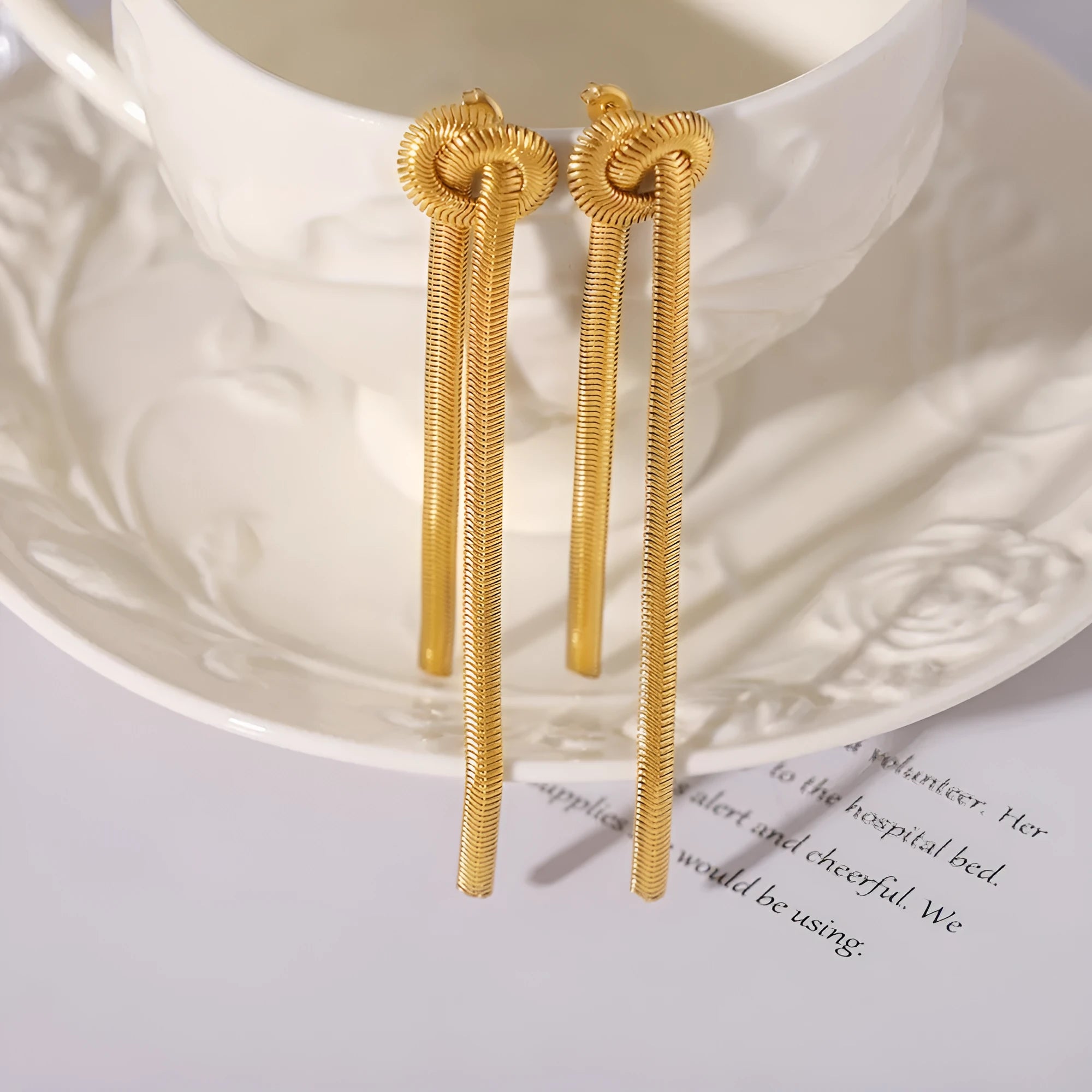 Gold knotted tassel pendant on long snake chain necklace with matching titanium steel earrings