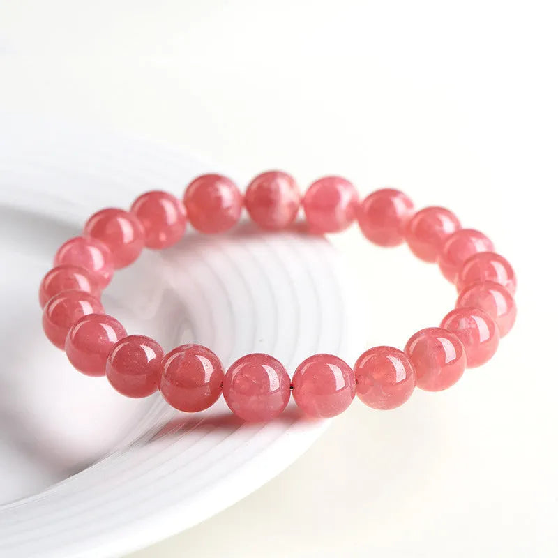Women's geometric Rhodochrosite crystal bracelet with Longevity Lock feature on a wrist, showing red patterned stone beads.