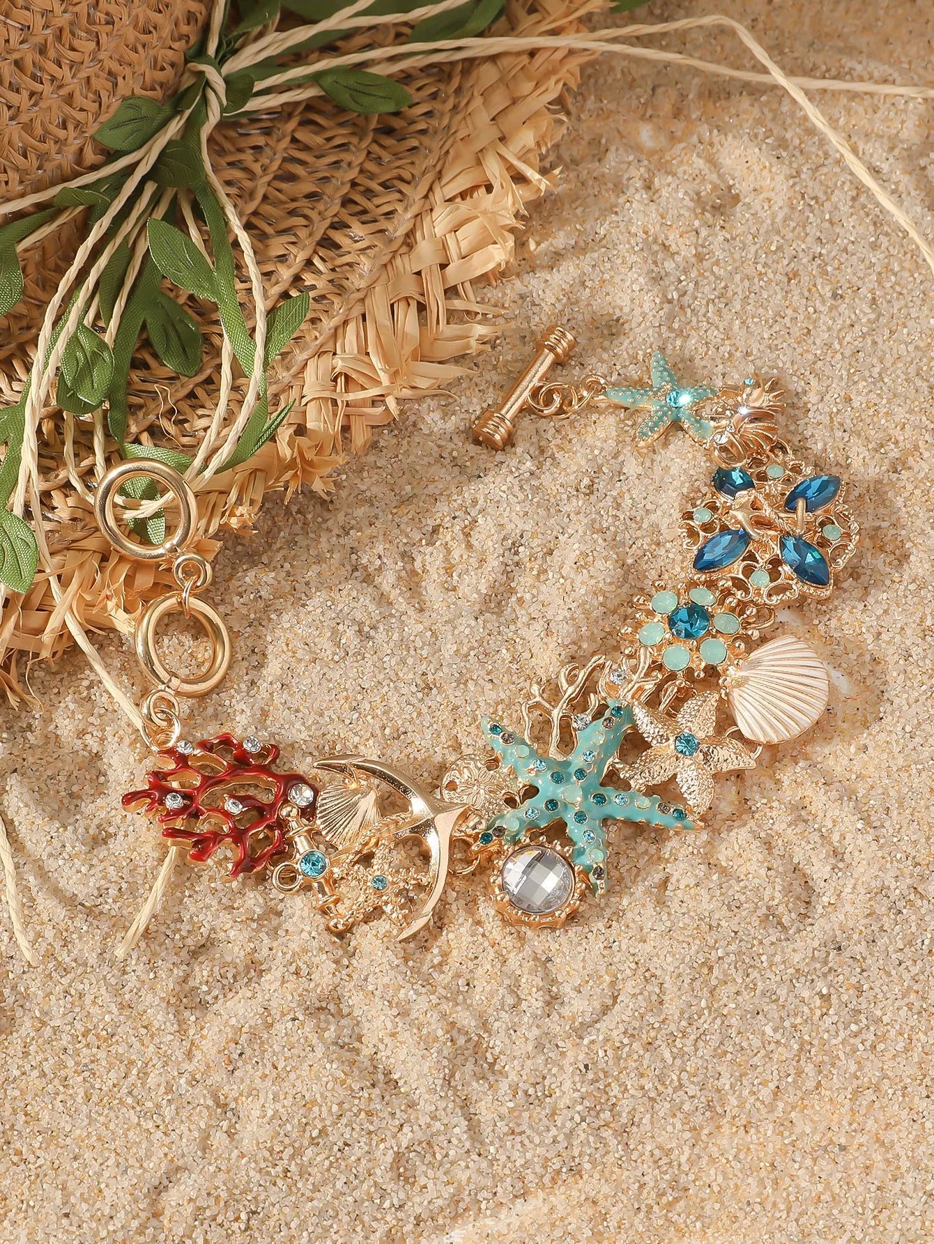 Alloy rhinestone bracelet with boat anchor and starfish charm in turquoise, red, or blue.