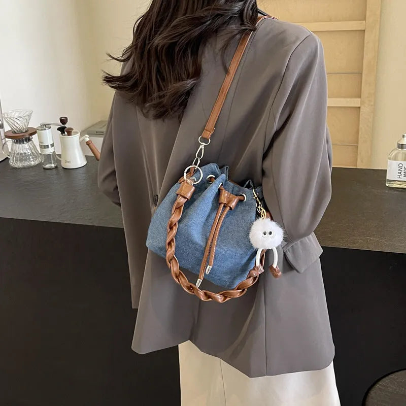 Blue one-shoulder cross body bucket bag with synthetic leather lining and hanging drop ornament