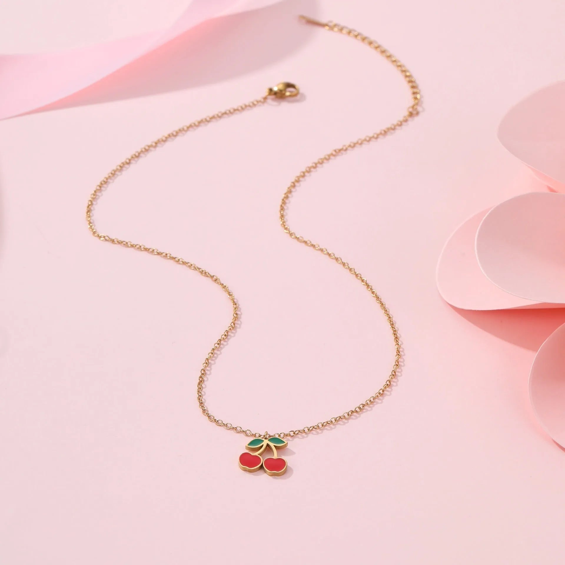 Cherry design jewellery set with gold plated necklace, bracelet, earrings, and ring on a flat surface.