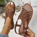 Black flat buckle open toe Roman style cross strap beach slippers on a plain background.