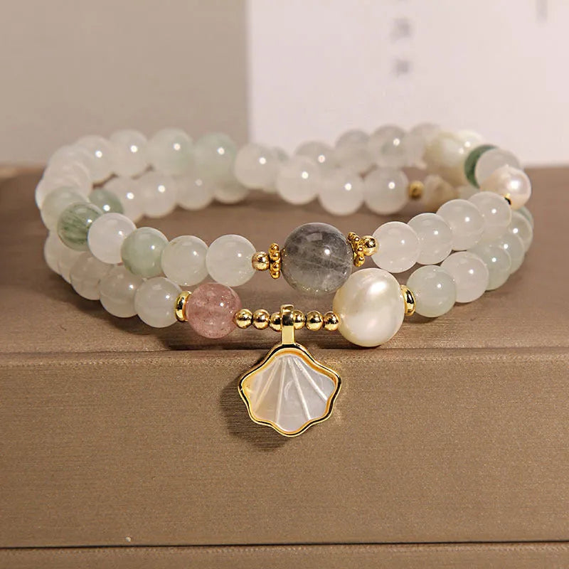 Women's crystal bracelet with gold ginkgo leaf pendant and rhinestones on a white background.