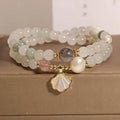 Women's crystal bracelet with gold ginkgo leaf pendant and rhinestones on a white background.