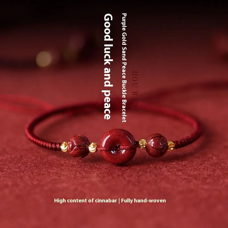 Close-up of a cinnabar heart charm on an adjustable black rope bracelet with a safety buckle.
